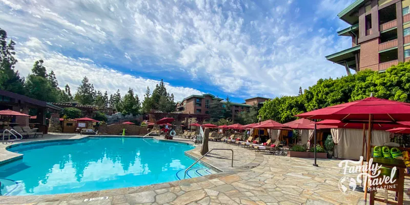 Pool at Grand Californian surrounded by trees with umbrellas and chairs 