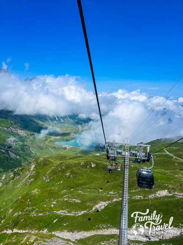 Gondolas above mountains with clouds and pond 