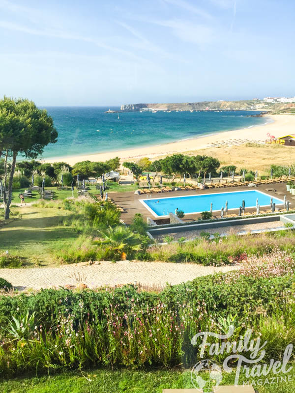Swimming pool view with beach in the background.