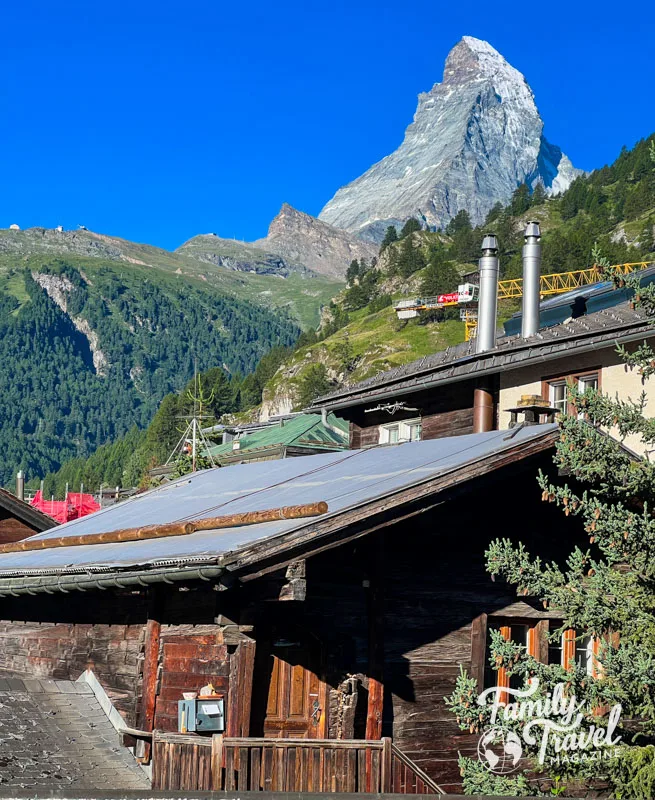 The Matterhorn above the town of Zermatt with other mountains and trees and buildings