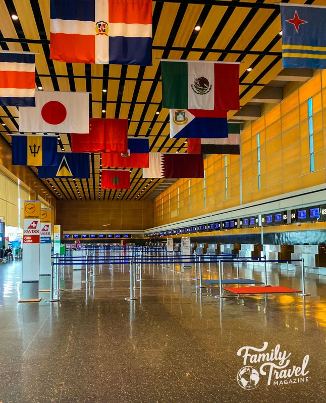 Flags hanging from ceiling in international terminal with empty check in desks
