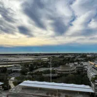 Panoramic overview of Orlando International airport with tour, parking garages, highway ramps and runways.