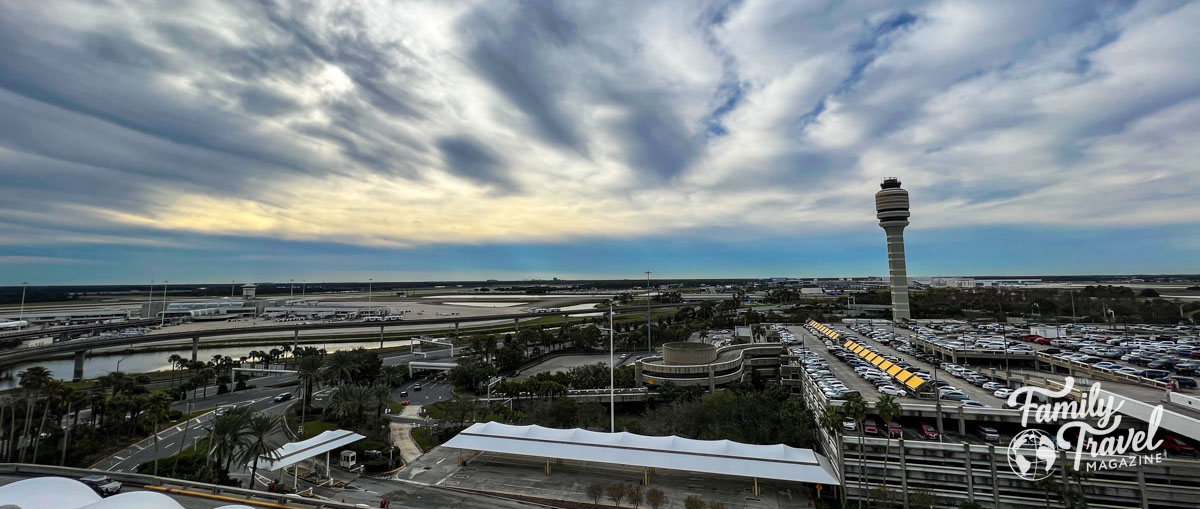 Panoramic overview of Orlando International airport with tour, parking garages, highway ramps and runways. 