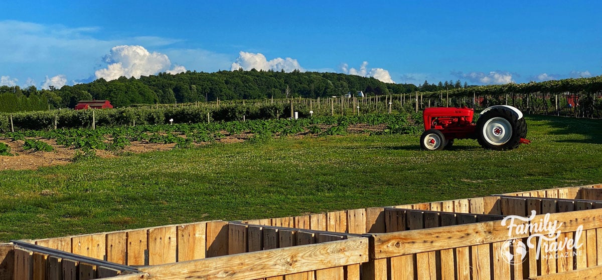 red tractor on farm with wooden bins in foreground.