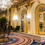 Lobby of the Copley Plaza hotel with marble, gilded gold, crystal chandelier, and flowers.