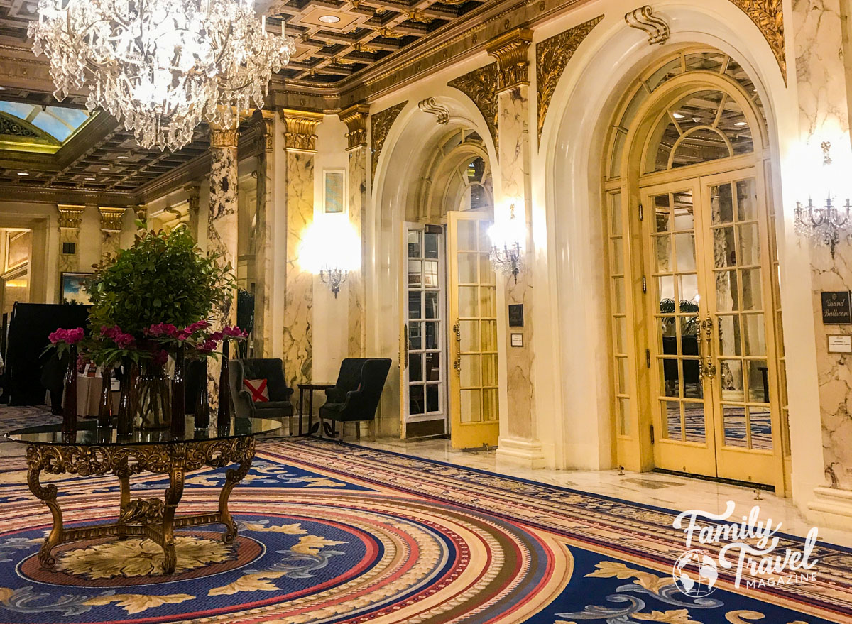 Lobby of the Copley Plaza hotel with marble, gilded gold, crystal chandelier, and flowers. 