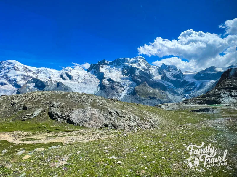 Snow capped mountains with greenery at the bottom