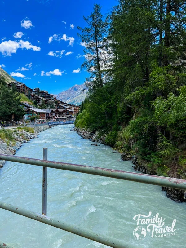 The Visp River surrounded by trees with buildings in background