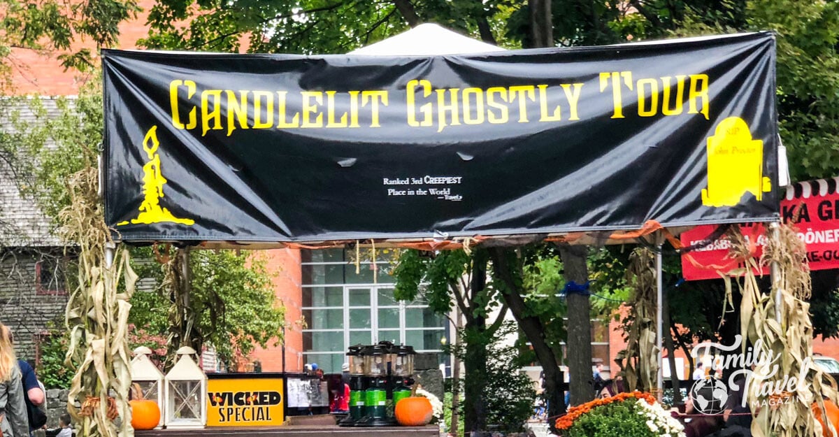 Booth for candlelit ghostly tour with mums, pumpkins, dried corn decor. 