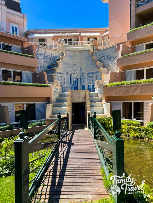 Olissippo Lapa Palace exterior entrance with tile work pink building and a footbridge over the pond. 