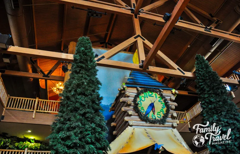 Clock tower surrounded by trees in wooden lobby of hotel 