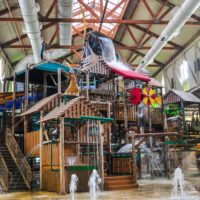 Indoor water park treehouse-style feature with sprays, water slides, buckets