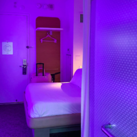 Hotel room at the Yotel with purple hint, showing tv, bed, small closet.
