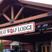 Wooden lodge inspired entrance to the Great Wolf Lodge with a-frame room and large boulders.