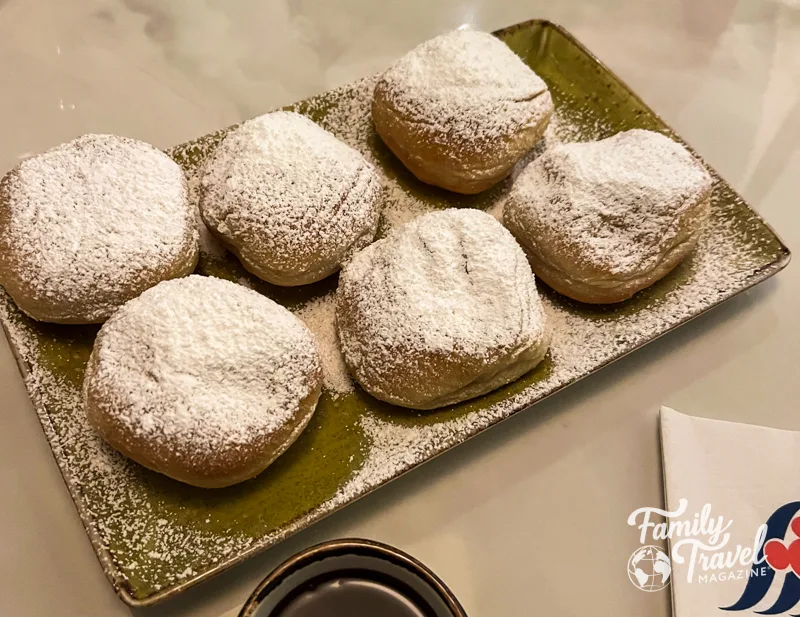 Six beignets with powdered sugar and chocolate sauce