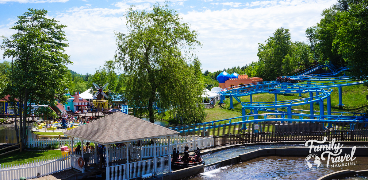 Story land panorama with river raft ride in foreground with roller coaster track in background.