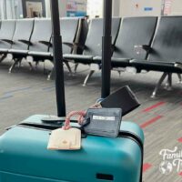 Teal suitcase in front of airport seats in gate waiting area