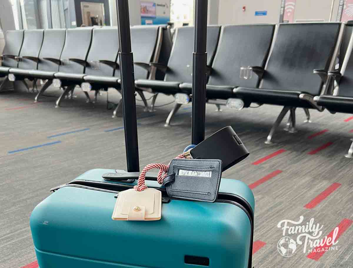Teal suitcase in front of airport seats in gate waiting area 