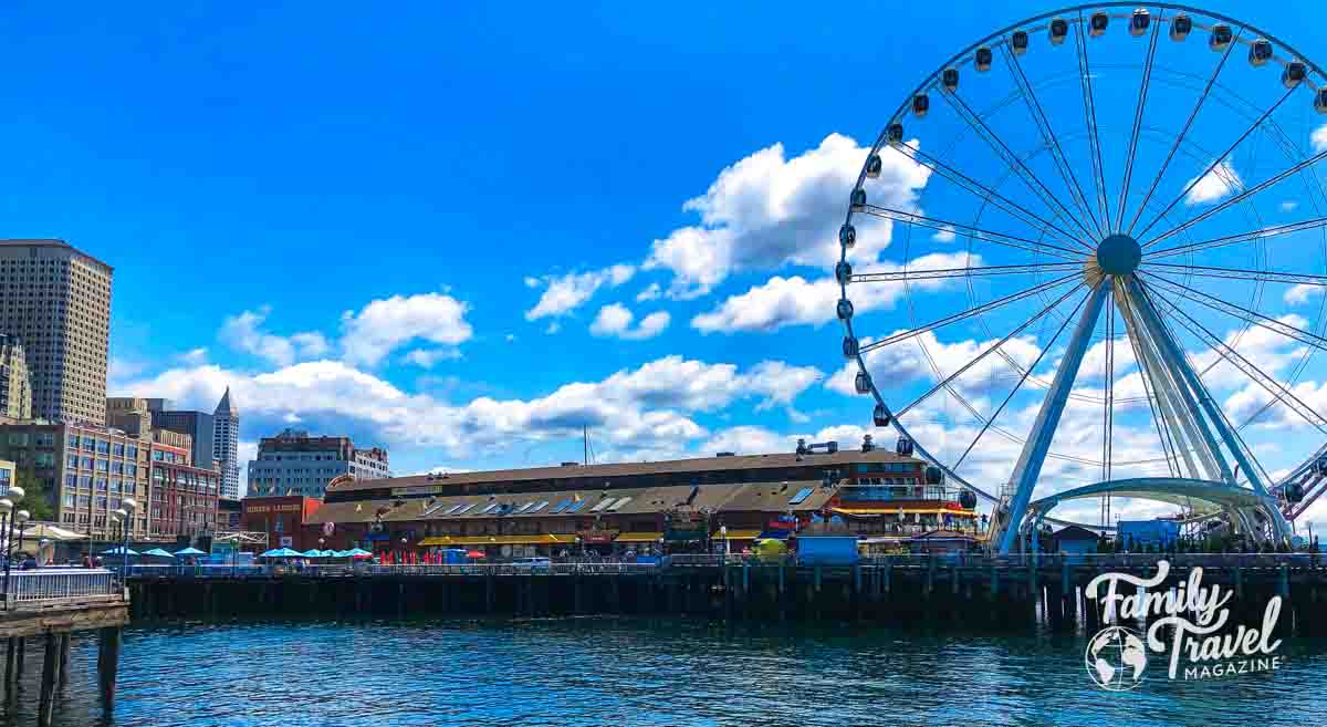 Ferris wheel on waterfront with building over pier