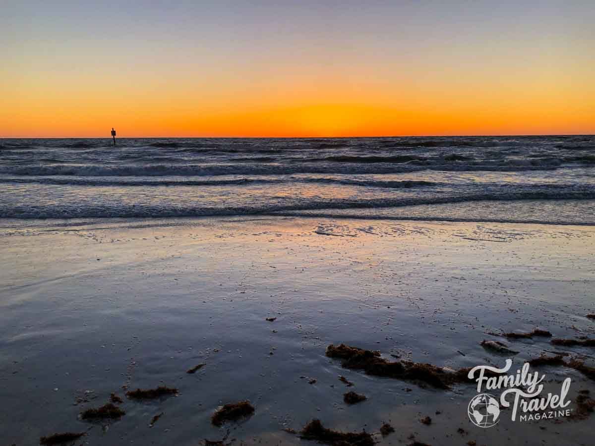 Bright orange sunrise over a calm ocean beach