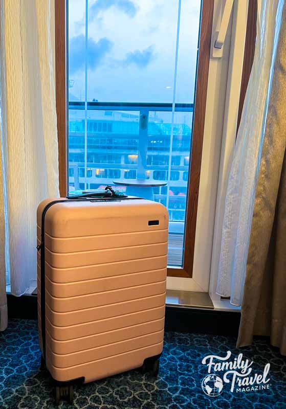 Pink suitcase in front of cruise ship balcony door