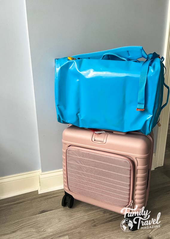 Bright blue bag on top of pink suitcase