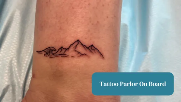 Tattoo parlor on board text with an image of a wave and mountain tattoo