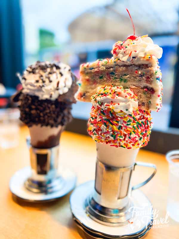 Two large shakes - one with a slice of cake and one with a brownie on top