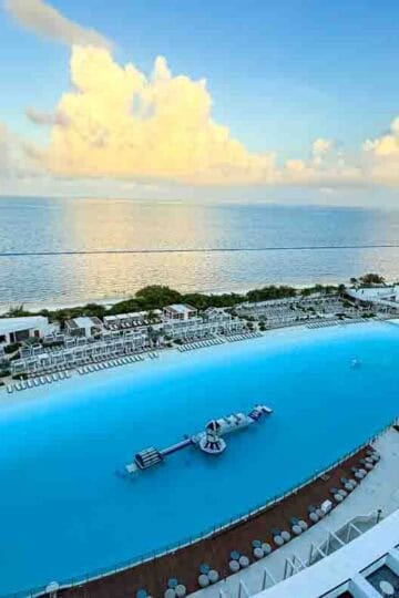 Aerial view of AVA Resort Cancun with expansive beachfront pool, oceanfront cabanas, and water playground at sunrise—perfect luxury getaway for families visiting Cancun, Mexico