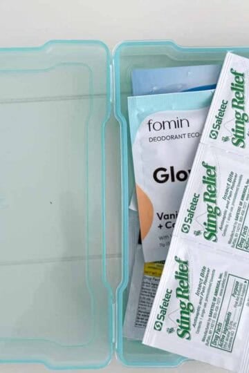 Travel essentials kit in a translucent blue case, containing insect bite sting relief wipes, deodorant wipes, and other personal care items—ideal for family vacations and packing convenience.
