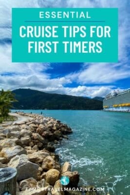 Essential cruise tips for first timers graphic with a large cruise ship docked in turquoise Caribbean waters, rocky shoreline, palm trees, and mountains in the background – Family Travel Magazine