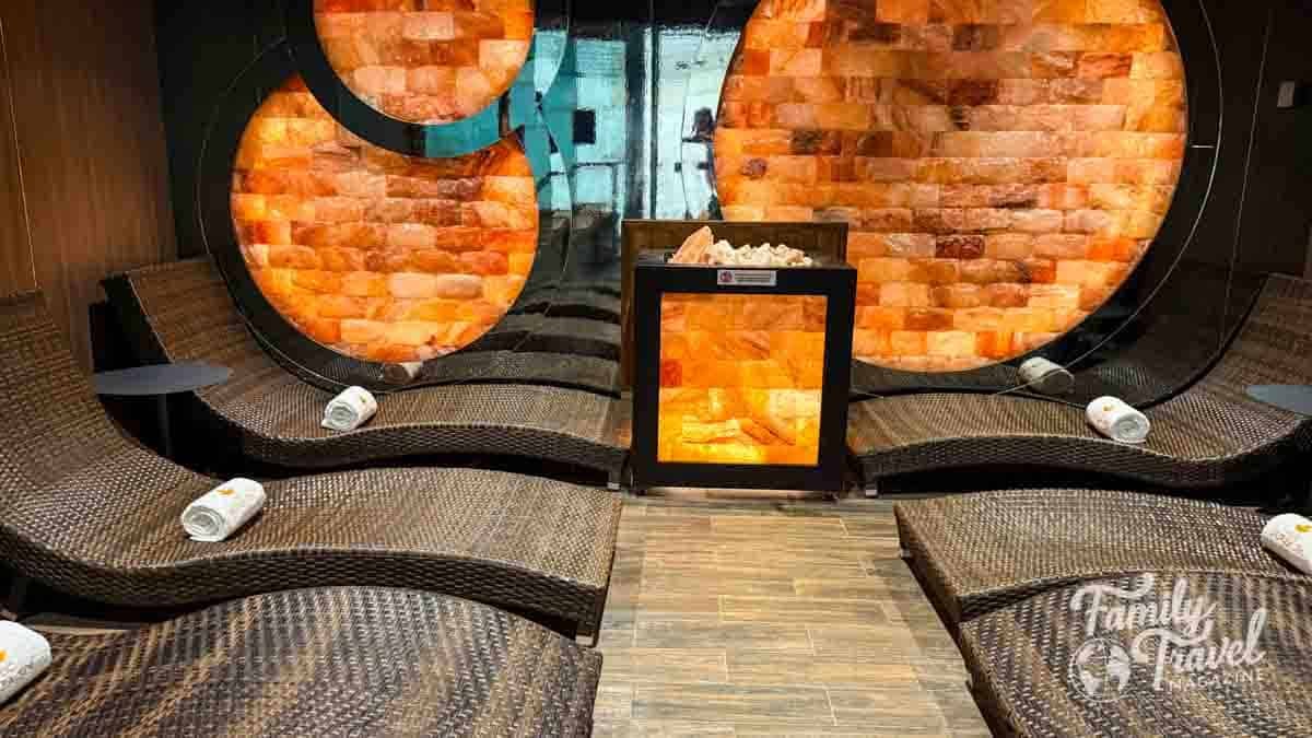 Wicker lounge chairs face a salt brick wall and a glowing salt lamp.