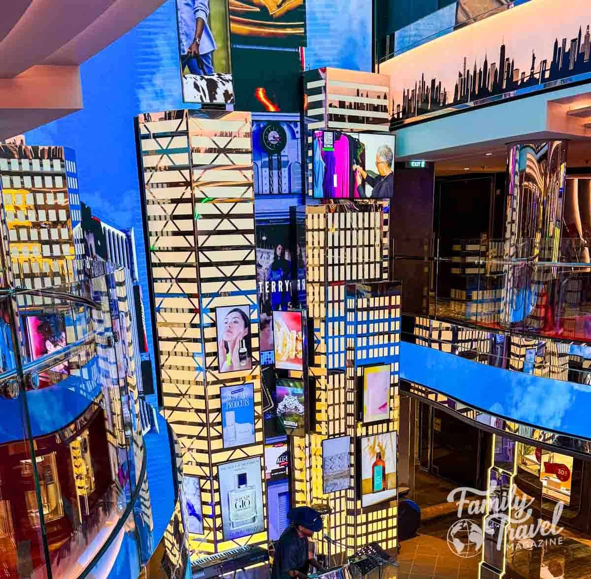 Abstract building-shaped displays with screens and a musician playing keyboard.