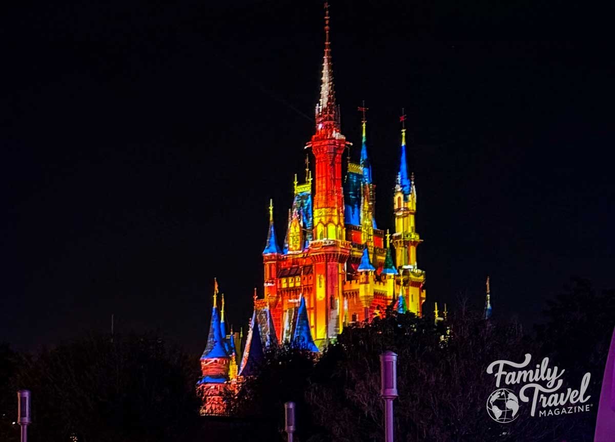 Cinderella Castle illuminated with vibrant colors against a dark night sky.