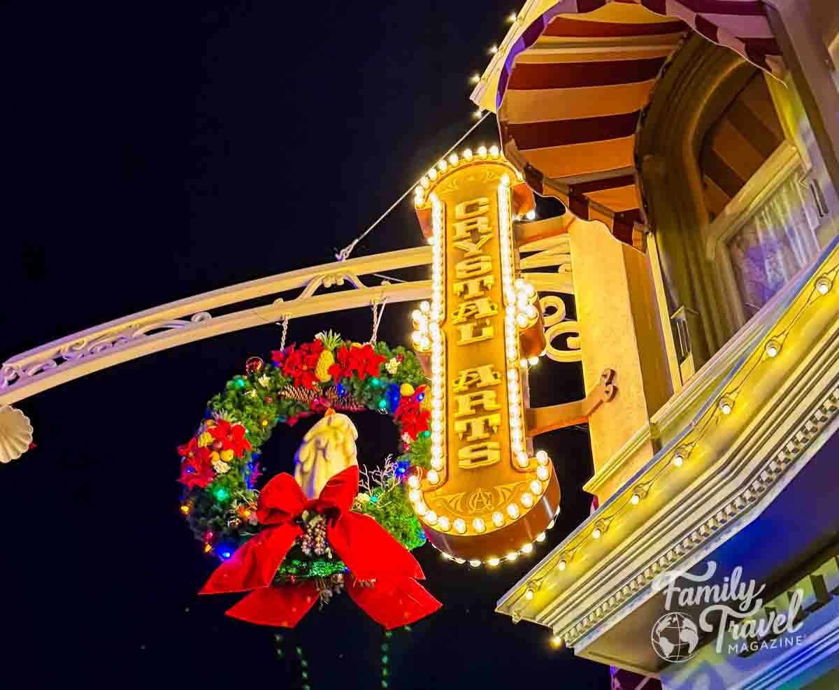 Illuminated Crystal Arts sign and Christmas wreath adorn a building at night.