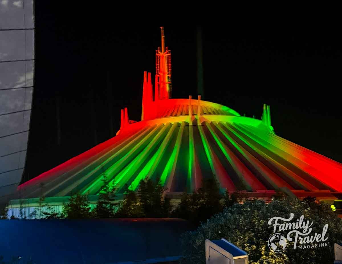 Space Mountain is illuminated with red and green lights at night.