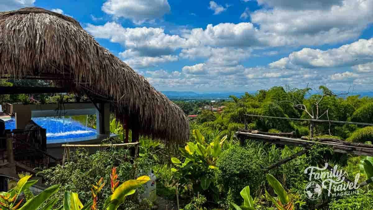 Thatched roof and pool overlooking Colombias Eje Cafetero coffee region with a distant town.