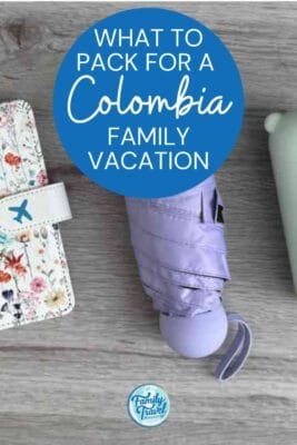 Floral passport holder and purple umbrella on wood for a Colombia family vacation.