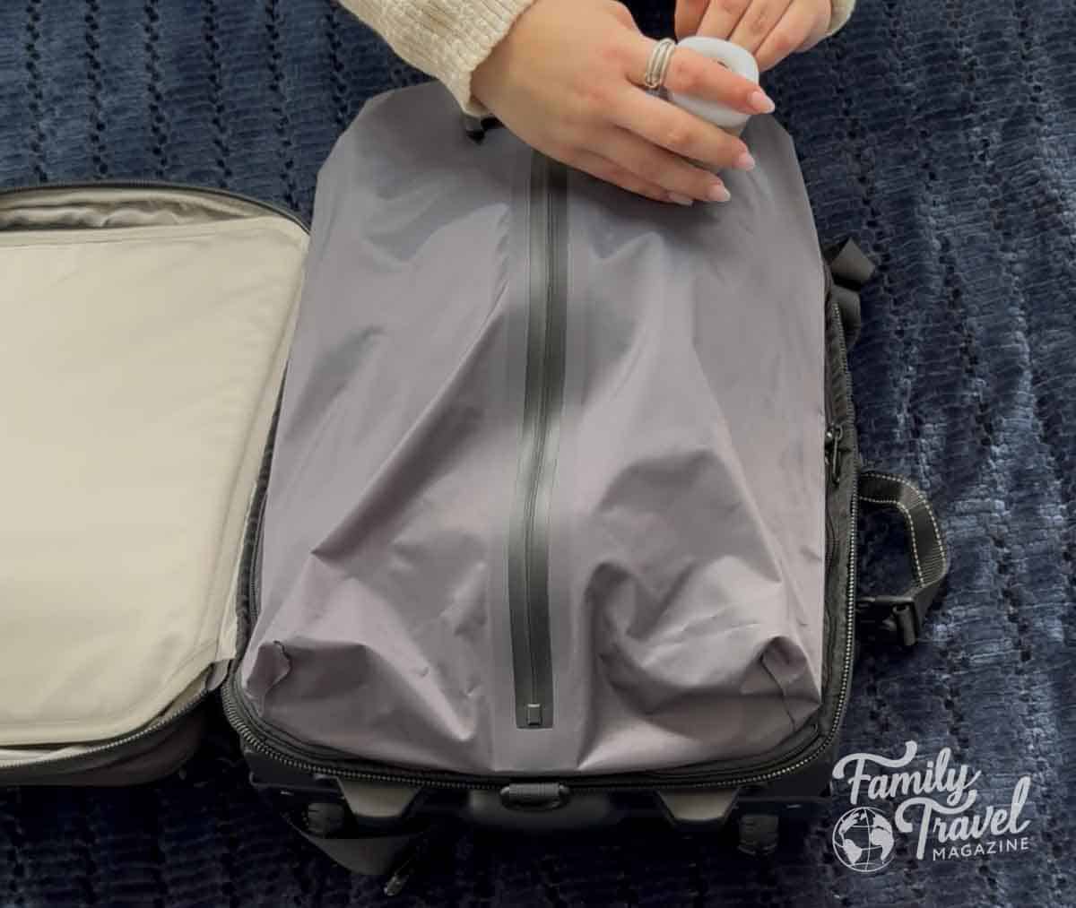 Traveler using an air pump compression bag inside a carry-on suitcase to maximize packing space and fit more clothes efficiently