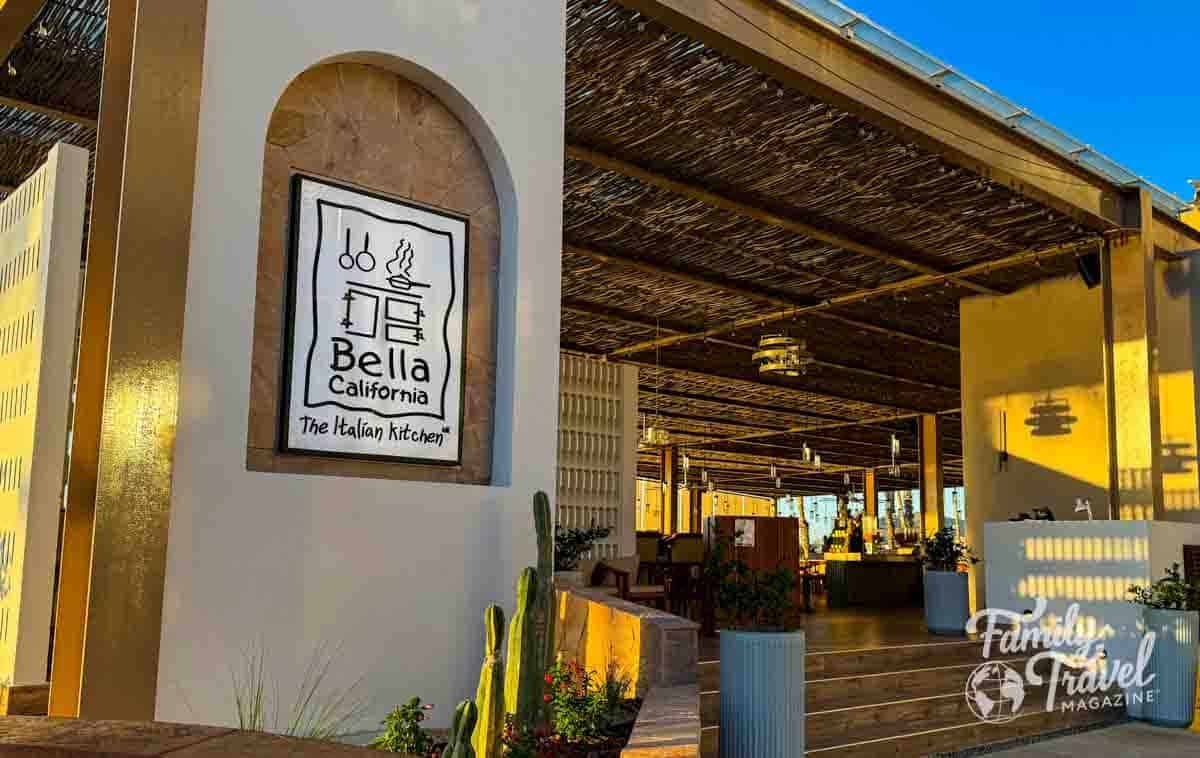 Bella California Italian Kitchen, an open-air restaurant with a thatched roof and desert plants at golden hour.
