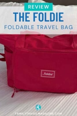 A hot pink the foldie foldable travel bag rests on a white textured surface.