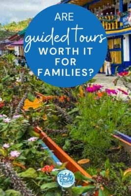 A vibrant blue and yellow building in Guatap&eacute;, Colombia, with lush flowers and greenery in the foreground.