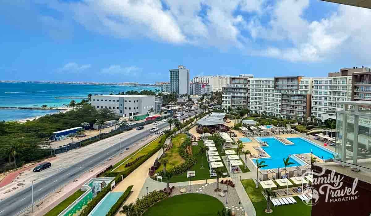 Aerial view of Aruba resort featuring resort pools, a busy road, and the turquoise Caribbean Sea.