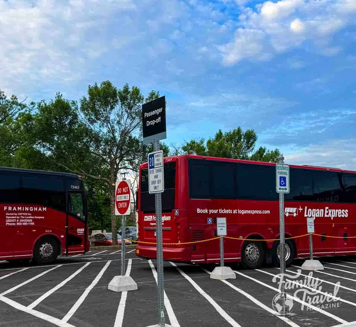Two red Logan Express buses at a passenger drop-off in Framingham, Massachusetts.