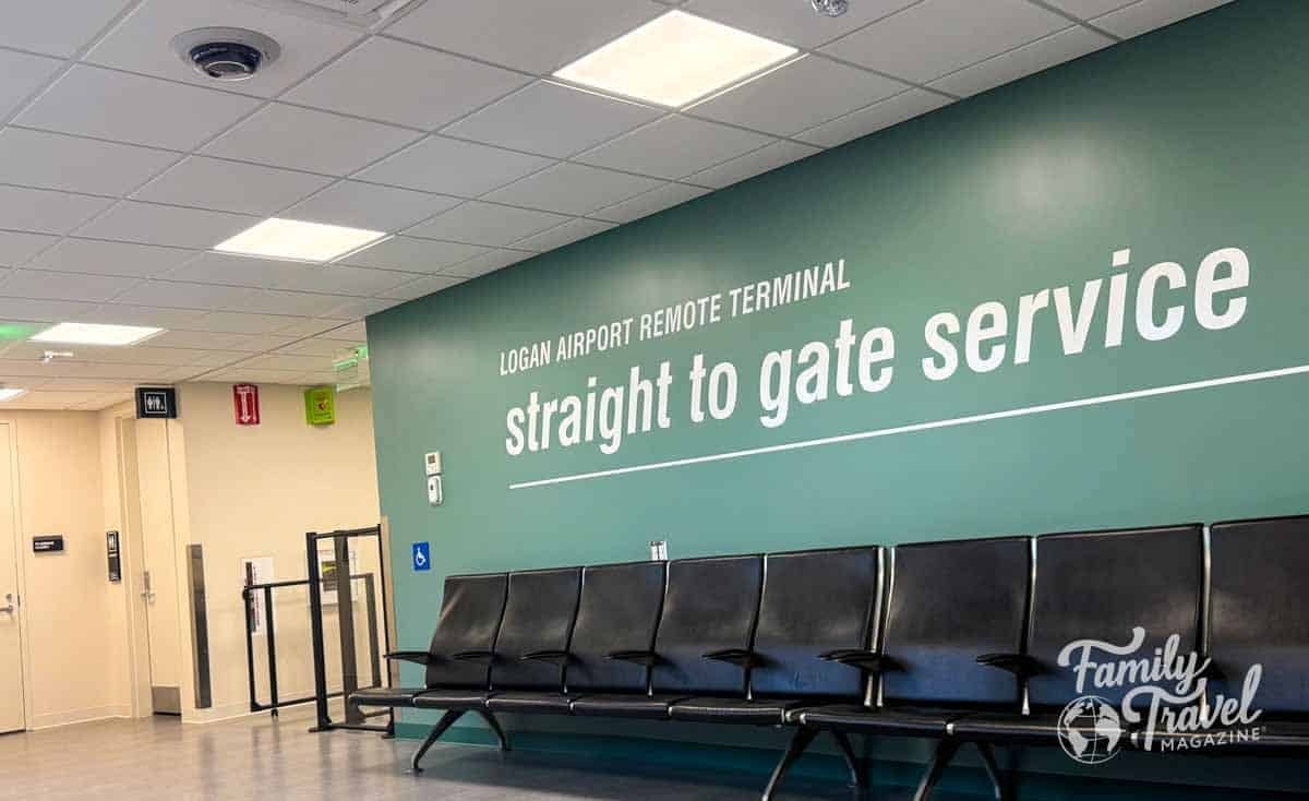 Logan Airport Remote Terminal waiting area with black chairs and a green wall advertising straight to gate service.