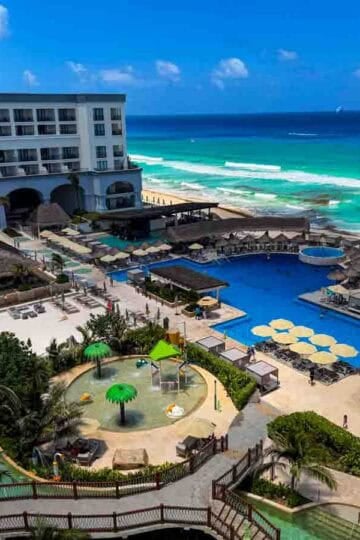 Aerial view of a luxurious family resort in Cancun, Mexico, with pools, a water park, and a turquoise beach.
