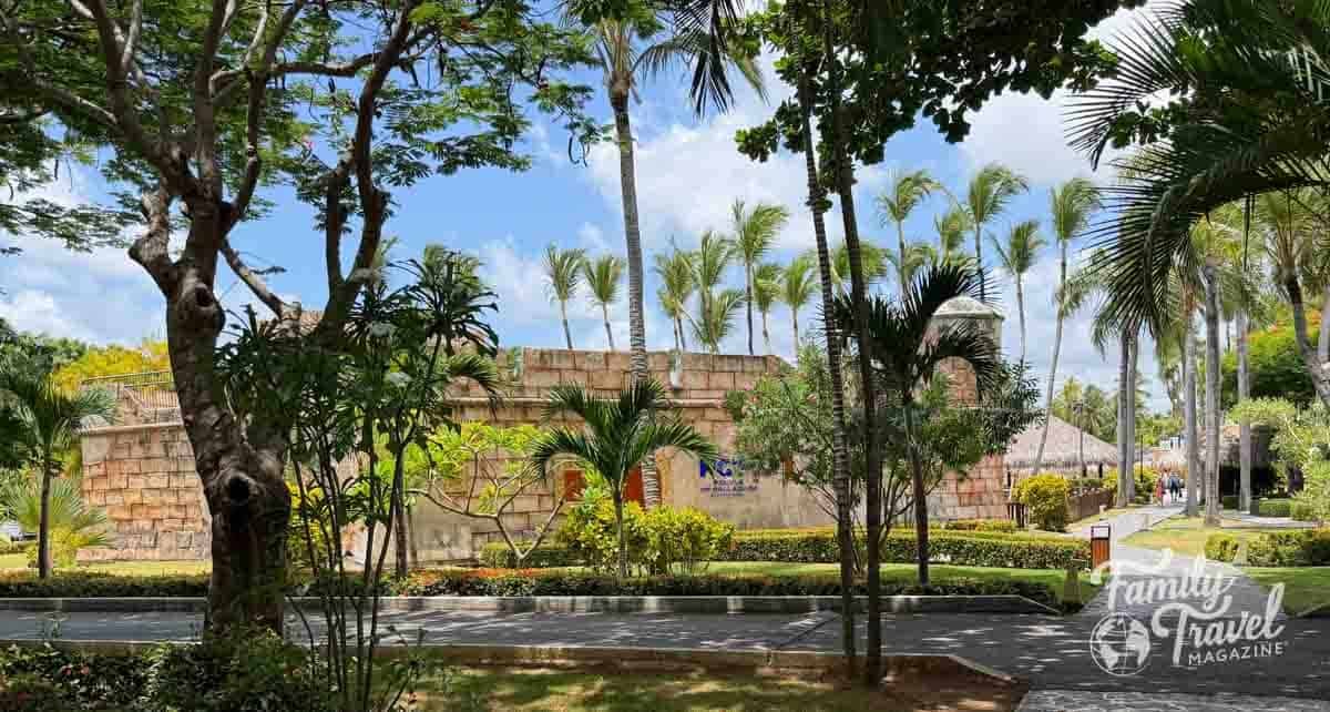 Lush palm trees frame a resort building with a fort-like tower at Now Larimar Punta Cana, Dominican Republic.