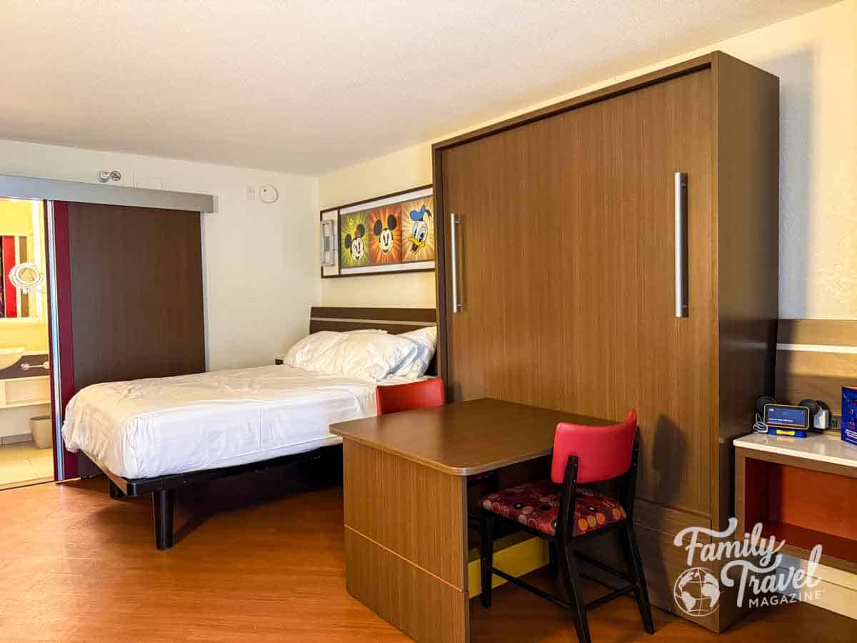 Renovated room at Disney’s All-Star Music Resort with queen bed, pull-down Murphy bed, table, and Disney wall art
