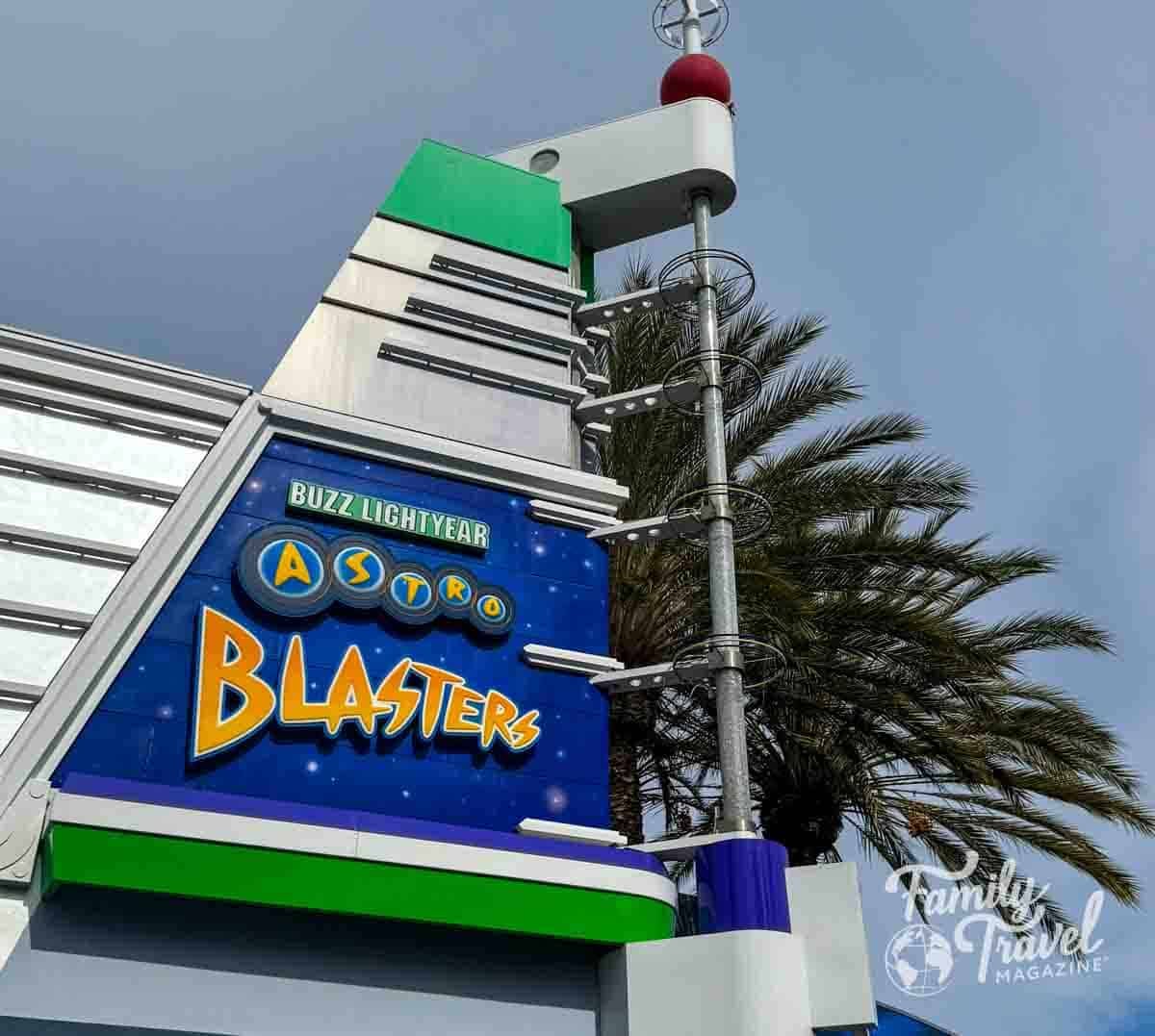 Buzz Lightyear Astro Blasters attraction sign at Disneyland, with a palm tree under a cloudy sky.
