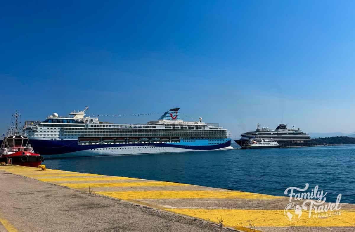 Two large cruise ships and the National Geographic Orion are docked at a concrete pier under a clear blue sky.